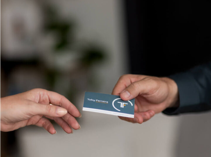 Toby Ferreira handing a business card to a client